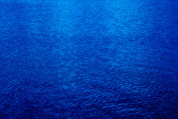 Fototapeta na wymiar Shining dark blue wavy water surface ripple background