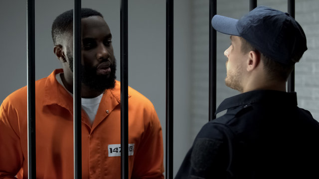 Afro-american prisoner making arrangement with prison guard, corruption in jail