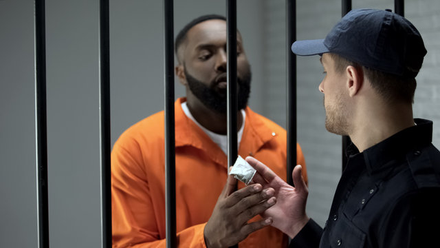 Prison guard giving afro-american imprisoned male dose of drugs illegal activity