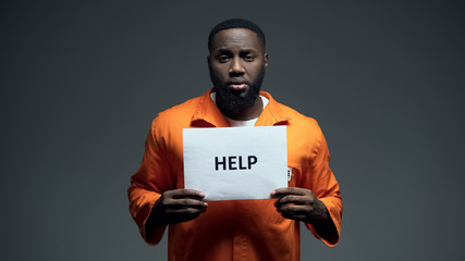 African-american male prisoner holding help sign, asking for justice, abuse