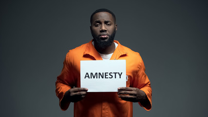 Afro-american prisoner holding amnesty sign, asking for help, human rights