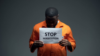 Fototapeta na wymiar Afro-american prisoner holding stop persecution sign, racial discrimination