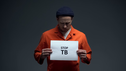 Fototapeta na wymiar Male prisoner holding Stop TB sign, healthcare in prison, life conditions