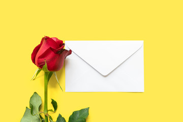 Fototapeta premium A single red rose and letter envelope on yellow background