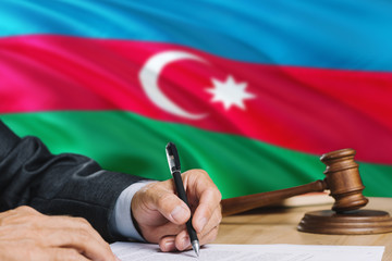 Judge writing on paper in courtroom with Azerbaijan flag background. Wooden gavel of equality theme and legal concept.