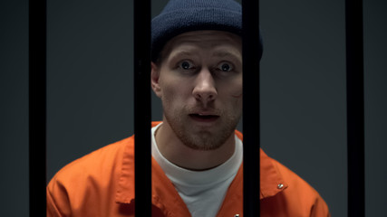 Arrogant prisoner throwing challenge, looking to camera, dangerous criminal