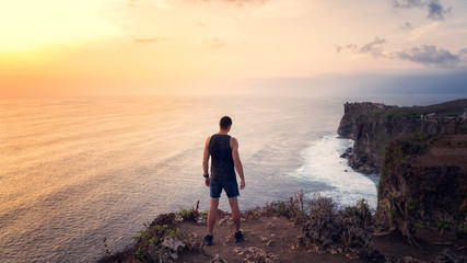 The guy stands back on the cliff Uluwatu Bali Indonesia