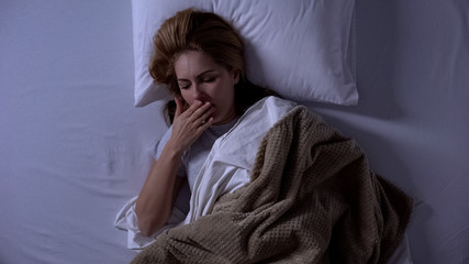 Blonde woman waking-up at night and feeling nausea, sickness, intestinal flu