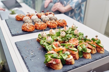 Italian bruschetta with chopped tomatoes, basil, mozzarella cheese and balsamic vinegar. Fresh homemade caprese bruschetta or crostini over black stone background, copy space.