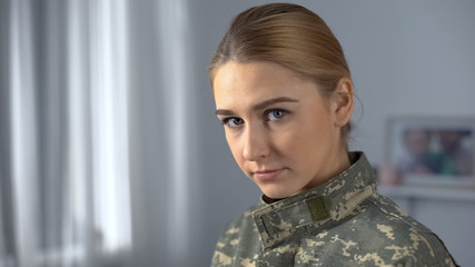 Confident female soldier student looking at camera, standing near academy window