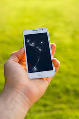 Hold the broken phone. Mobile phone with broken screen.