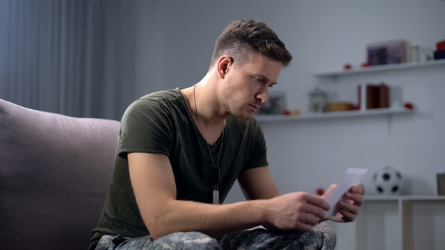 Disappointed soldier looking at family photo, relationship problem, break-up