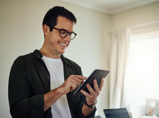 Smiling man using digital tablet at home
