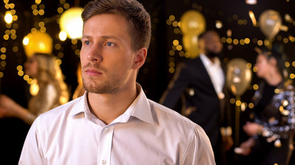 Worried handsome man waiting for girlfriend at party looking around, loneliness