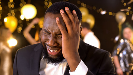 African american male suffering strong migraine at party, alcohol overdose