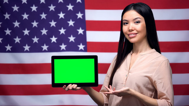 Girl holding tablet with green screen, USA flag on background, migration - Powered by Adobe