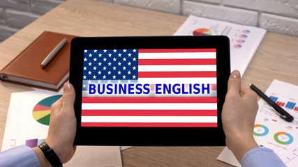 Business English application against USA flag on tablet in female hand, tutorial