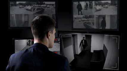 Security man monitoring corporate surveillance camera indoors, safety concept