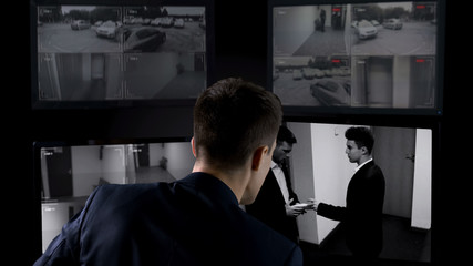 Security operator watching transfer of bribe on CCTV footage, safety concept