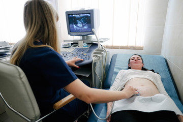 Pregnant woman in the Hospital, Close-up Shot of the Doctor does Ultrasound / Sonogram Procedure to a Pregnant Woman.