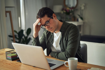 Portrait of stress sad man working on laptop at home