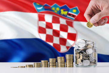 Business man holding coins putting in glass, Croatia flag waving in the background. Finance and business concept. Saving money.