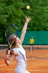 Young female tennis player serving.