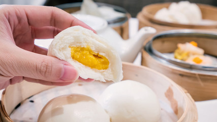 Delicious dim sum, famous cantonese food in asia, fresh and hot salted creamy custard buns in bamboo steamer in hong kong yumcha restaurant, close up