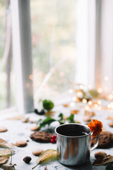 Cup with tea near the window with autumn leaves and cookies