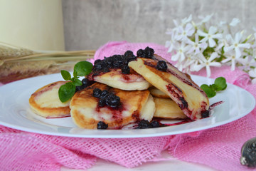 Stack of pancakes or fritters with blueberry jam and berries on.