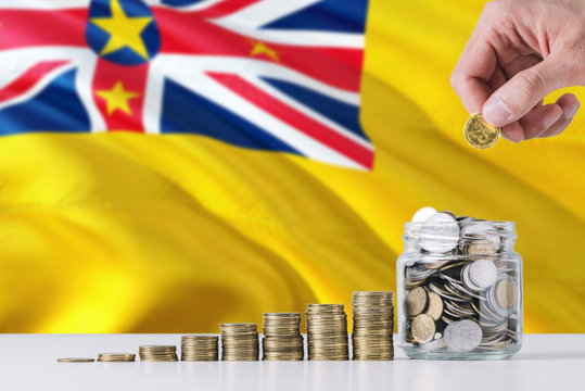 Business man holding coins putting in glass, Niue flag waving in the background. Finance and business concept. Saving money.