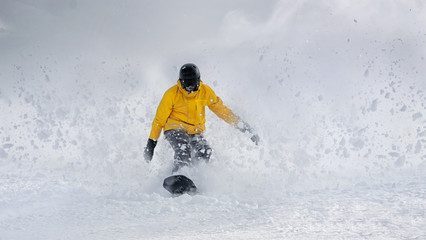 Fototapeta na wymiar Man snowboarder rides beating out of the snow freeride