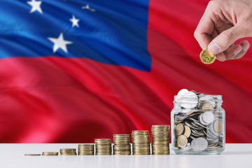 Business man holding coins putting in glass, Samoa flag waving in the background. Finance and...