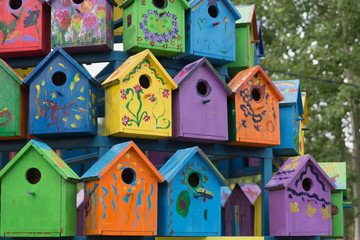 Many bright colorful wooden birdhouses (nesting boxes) located close to each other, painted by little kids