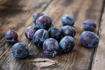 Fresh organic plums on old wooden table.