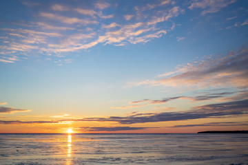 Obraz premium The sun setting over a frozen harbor in rural Prince Edward Island, Canada.......