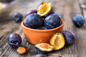 Fresh organic plums on old wooden table.