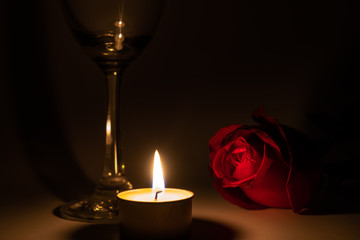 Tealight candle, wine glass and rose