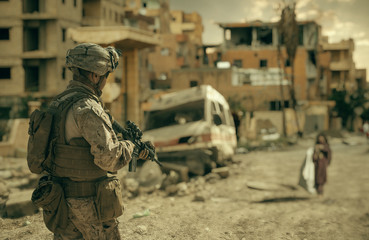 Military soldier walking in destroyed city and looking at homeless girl