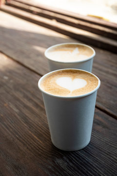 Two White Paper Cups Of Coffee On Wooden Table.