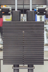 Black iron heavy plates stacked from the weight of the machine in the fitness room. Sport equipment.