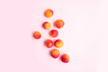 Fototapeta na wymiar Flat composition of ripe tasty peaches with red side on a pink background.
