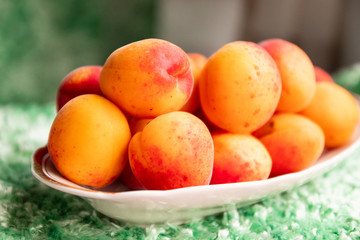 Ripe apricots in a plate on a green background