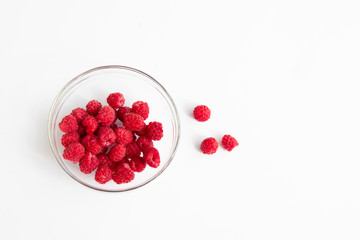 Red fresh raspberries in a glass bowl
