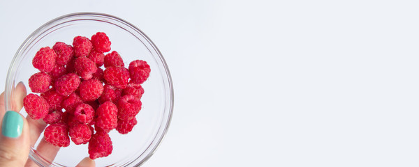 Freshly harvested raspberries in a glass bowl.