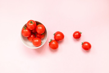 Creative layout made of pink ceramic bowl with ripe red tomatoes on a pink background.