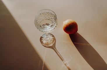 Summer themed Food Photography still life: Crystal champagne glass of water and a lemon casting a...