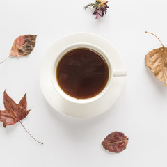 Hot beverage with dry leaves on white surface