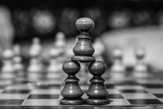 Black and white photo of a pyramid made out of pawns symbolising unity among common people
