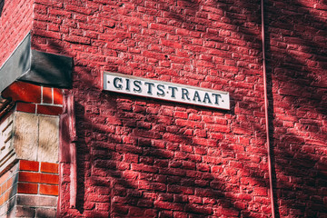 Delft / Netherlands - 08.19.2019: Giststraat street sign with a beautiful red brick pattern background